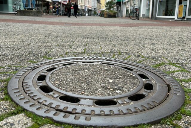 Ein Gully in einer Fußgängerzone.