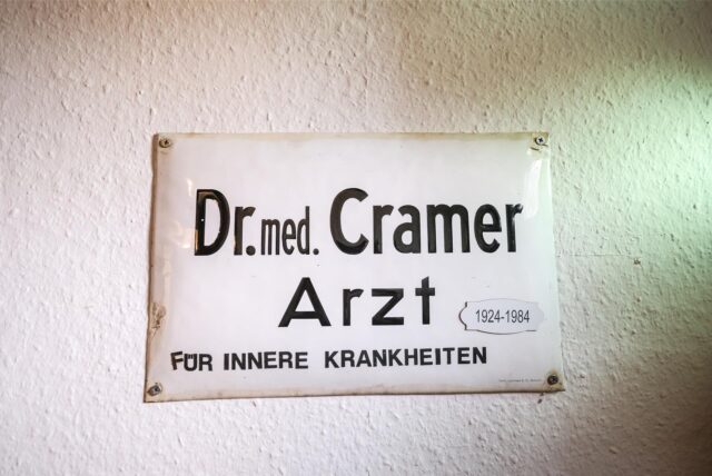 Auf einem alten Blechschild im denkmalgeschützten Haus Cramer in der Altstadt von Recklinghausen steht: Dr. med. Cramer – Arzt für inneren Krankheiten. Dazu die Angabe 1924 bis 1984.