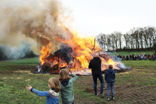Drei Kinder und ein Erwachsener stehen vor dem Osterfeuer von Bauer Karl Godde aus Herten-Disteln.