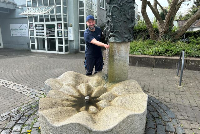 Kim Siemko von den Hertener Stadtwerke steht hinter einem Brunnen.