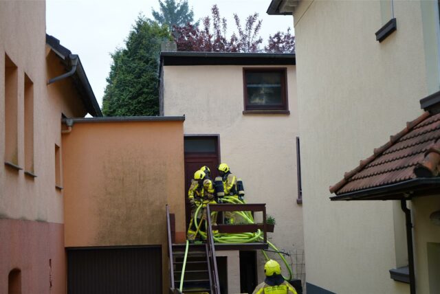Feuerwehrleute vor der Werkstatt-Tür in einem Hinterhof an der Thomasstraße in Castrop-Rauxel.