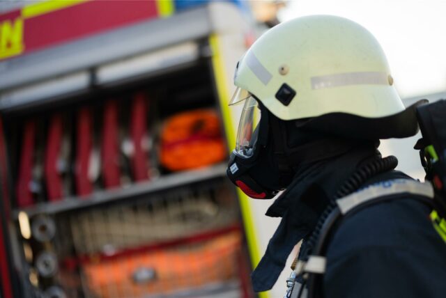 Ein Feuerwehrmann in Atemschutzausrüstung steht an einem Einsatzfahrzeug an der Feuerwache der Feuerwehr Leverkusen.
