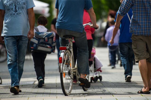 Ein Radfahrer schlängelt sich zwischen Fußgängern hindurch.