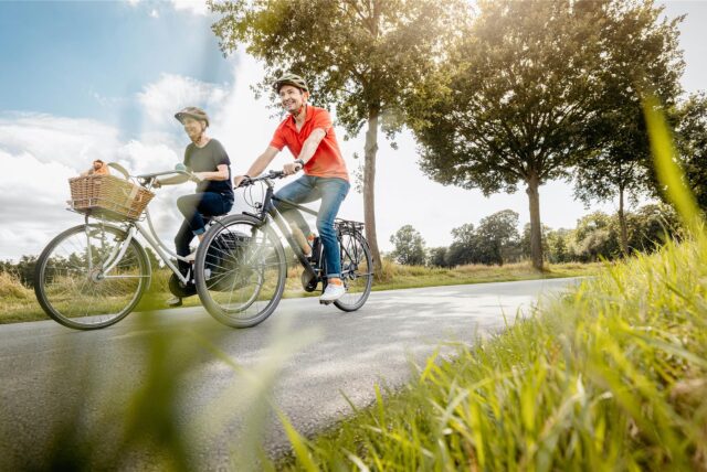 Zwei Radfahrer fahren auf einem Radweg im Grünen.
