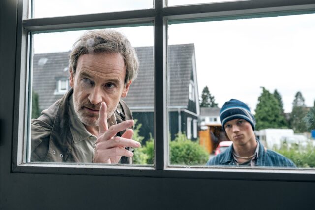 Hauptkommissar Peter Faber (Jörg Hartmann) und Finn Gebken (Caspar Hoffman, r), Sohn der toten Meike Gebken stehen im Dortmund-Tatort „Feuer“ vor einem Fenster.
