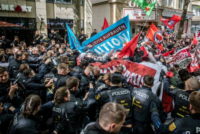 Schwarz uniformierte Polizisten und Demonstranten mit Flaggen geraten aneinander.