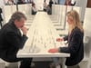 Yoko Onos „Play it by Trust“ lädt in der Neuen Nationalgalerie bis zu 20 Besucher zum Schachspielen an einer langen weißen Tafel ein.