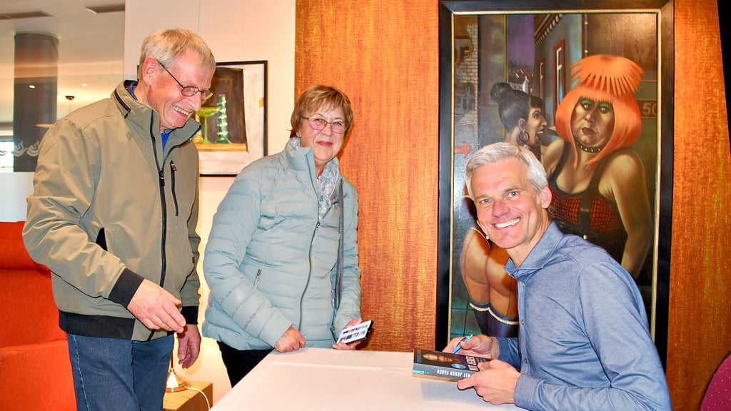 Nach seiner Lesung im Arthotel Havelberg signiert  Ironman und Nachrichtensprecher Thorsten Schröder sein Buch „Mit jeder Faser“. Ingrid und Olaf Rambeau fühlen sich durch ihn bestärkt darin, dass Bewegung wichtig ist.