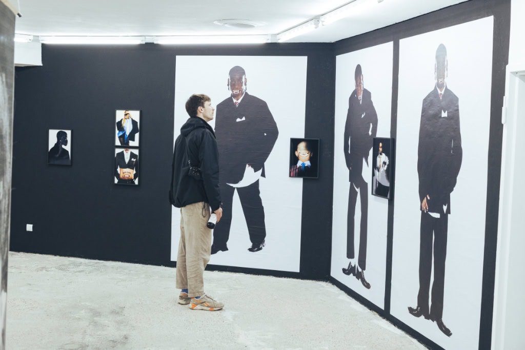 Mann betrachtet großformatige Porträts und Collagen in moderner Kunstausstellung bei einem Festival in Köln.