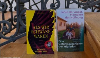 Auf einer Holztreppe stehen zwei Bücher, dahinter ein verschnörkeltes Eisengeländer