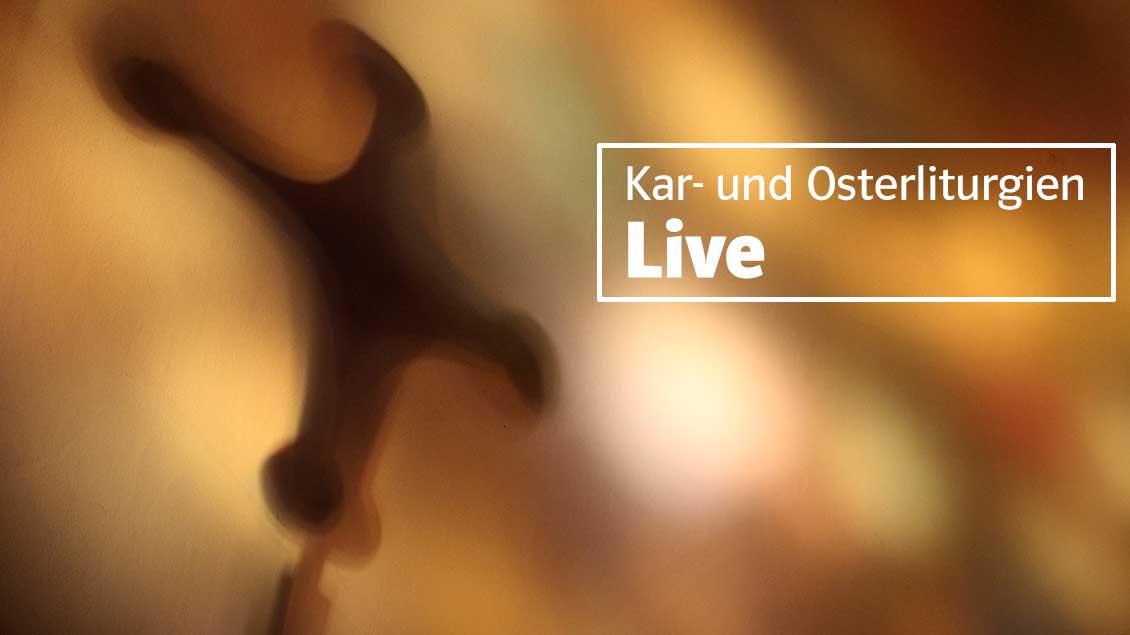 Ein Kreuz wirft Schatten auf eine Wand mit goldenen Lichtreflexen Foto: Martin Schmitz