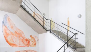 Zu sehen ist ein Treppenhaus das von Kateryna Lysovenko bemalt wurde. Auf den weißen Wänden sind zarte Malereien menschlicher Wesen zu sehen.