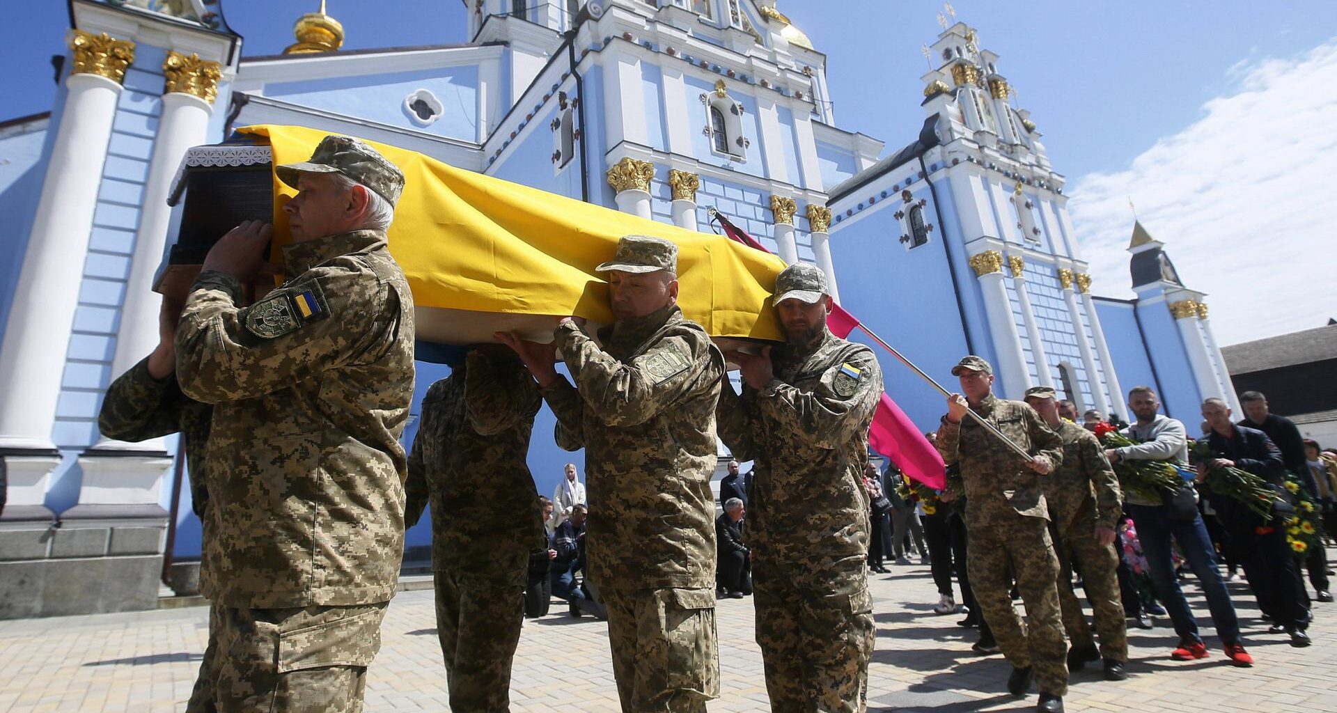 Soldaten tragen einen Sarg, der mit einer ukrainischen Flagge bedeckt ist.