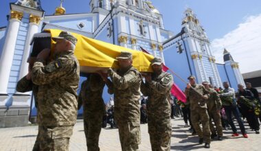 Soldaten tragen einen Sarg, der mit einer ukrainischen Flagge bedeckt ist.