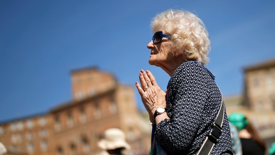 Eine alte Frau betet auf dem Petersplatz © picture alliance/dpa/AP | Francisco Seco 