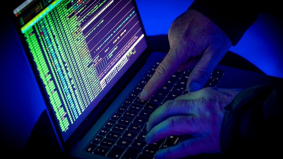 Eine Person in einem dunklen Raum tippt etwas in einen Laptop ein. © dpa picture alliance Foto:  Jochen Tack