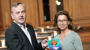 Thomas Fuchs (l), Hamburgischer Beauftragter für Datenschutz und Informationsfreiheit, übergibt den 33. Tätigkeitsbericht an Carola Veit (SPD), Präsidentin der Hamburgischen Bürgerschaft, im Plenum des Rathauses. © picture alliance/dpa | Marcus Brandt Foto: Marcus Brandt