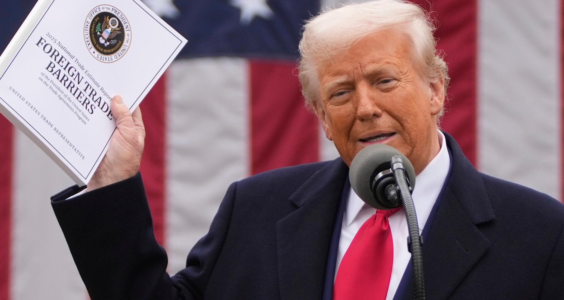 Präsident Trump spricht in im Garten des Weißen Hauses in ein Mikrofon. Er hält eine Mappe mit Zollankündigungen hoch. 2.4.2025