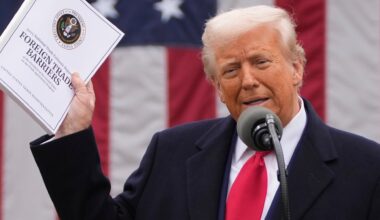 Präsident Trump spricht in im Garten des Weißen Hauses in ein Mikrofon. Er hält eine Mappe mit Zollankündigungen hoch. 2.4.2025