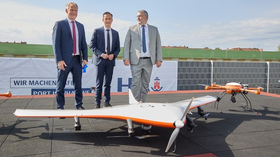 Jens Meier, CEO der HPA (Hamburg Port Authority), Falk Schnabel, Polizeipräsident, und Andreas Richter, Abteilungsleiter Innovation und Cluster bei der Behörde für Wirtschaft und Innovation (BWI), stehen während der Eröffnung des "dronePORT" am Kleinen Grasbrook hinter einer Drohne. © picture alliance / dpa Foto: Georg Wendt