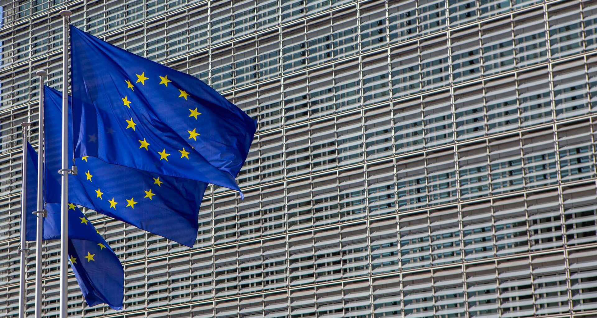 Das Berlaymont-Gebäude in Brüssel, der Sitz der Europäischen Kommission. Davor wehen drei Europafahnen.