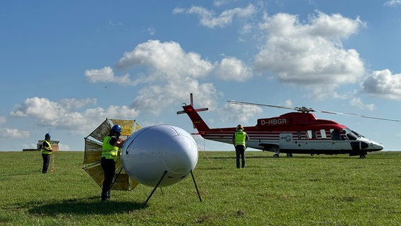 Hubschrauber der BGR über dem Wald am Sumpfteich in Buntenbock bei Clausthal-Zellerfeld im Harz. Mit dem weißen Messinstrument kann die magnetische Struktur des Bodens in bis zu 1000 Meter Tiefe gemessen werden. Daraus könne Forscher Rückschlüsse auf mögliche Erzvorkommen ziehen. © Bundesanstalt für Geowissenschaften und Rohstoffe (BGR) 