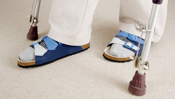 Die Aufnahme zeigt die Füße einer Person, die Sandalen trägt und an Krücken geht. © Fotolia Foto: Andy Nowack