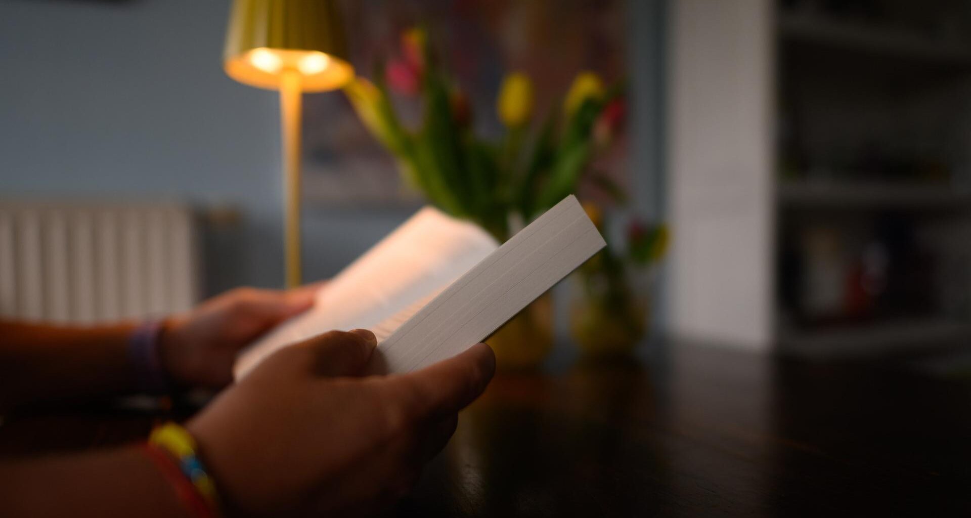 Eine Frau liest an einem Küchentisch ein Buch. (gestellte Szene)