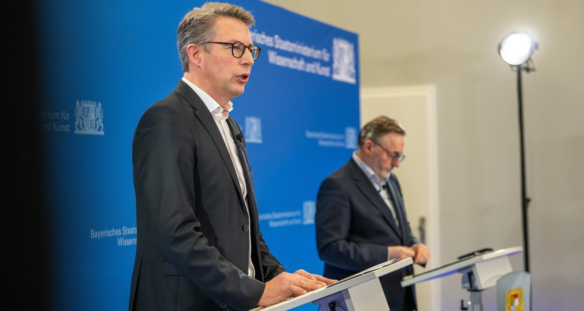 Markus Blume, ein Mann mittleren Alters in dunklem Anzug, spricht bei einer Pressekonferenz ins Mikrofon. Rechts neben ihm steht Anton Biebl, ebenfalls mittleren Alters, ebenfalls im dunklen Anzug und mit ernstem Gesichtsausdruck.