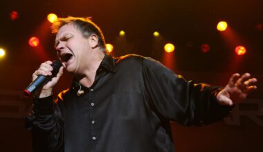 Ein Mann steht mit ausgebreiteten Armen auf einer Bühne und singt. In der rechten Hand hält er ein Mikrofon. Es ist der US-Rockmusiker Meat Loaf.