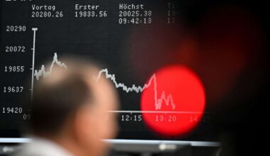Ein Börsenhändler nimmt am Parketthandel in Frankfurt teil. Im Hintergrund ist die fallende DAX-Kurve zu sehen. An der Börse sehen in diesen Tagen viele rot.