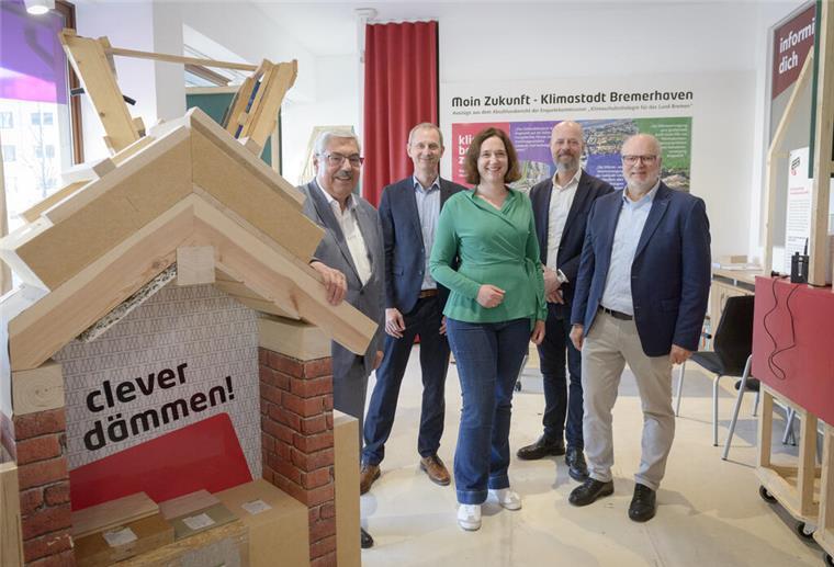 Eine Personengruppe steht in einem Raum mit Ausstellungsstücken zur Wärmedämmung