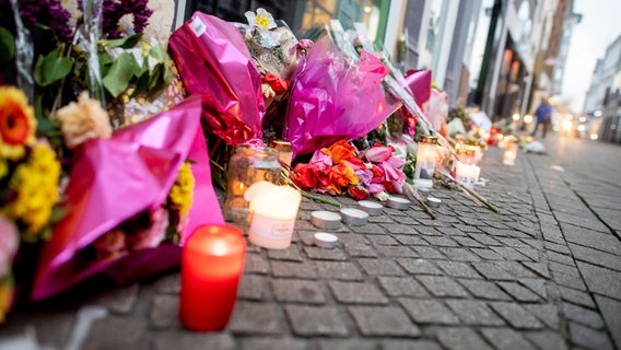 Zahlreiche Blumen und Kerzen stehen in der Oldenburger Innenstadt an einer Hauswand in der Achternstraße, in der am frühen Sonntagmorgen ein Mensch von Schüssen aus einer Polizeiwaffe tödlich verletzt wurde. © dpa Foto: Hauke-Christian Dittrich