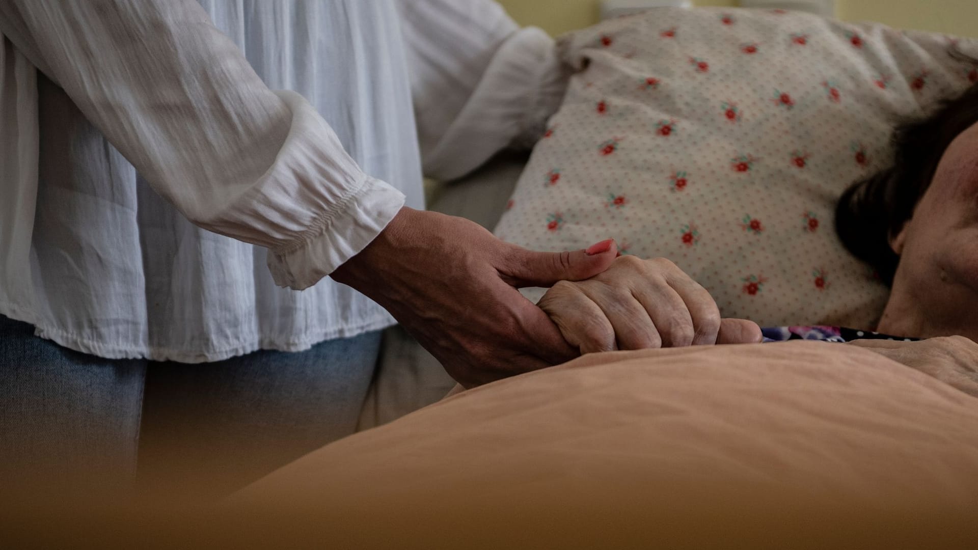 Pflegeheim (Symbolbild): Eine Frau hält die Hand einer Pflegebedürftigen.