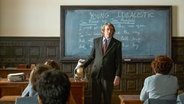 Szene aus dem Film "Der Pinguin meines Lebens": Ein Lehrer und ein Pinguin stehen im Klassenzimmer vor Schülern. © TOBIS Film GmbH 