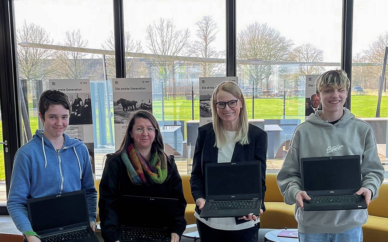 Zwei Erwachsene und zwei Kinder mit Laptops.