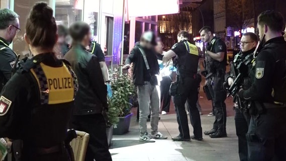 Mehrere Polizistinnen und Polizisten kontrollieren eine Gruppe Männer auf der Straße. © Nonstopnews 