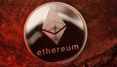 Eine glänzende silberne Ethereum-Münze, die stolz ihr unverwechselbares Logo präsentiert, ruht elegant auf einer strukturierten Holzoberfläche unter einem eindrucksvollen roten Schein.