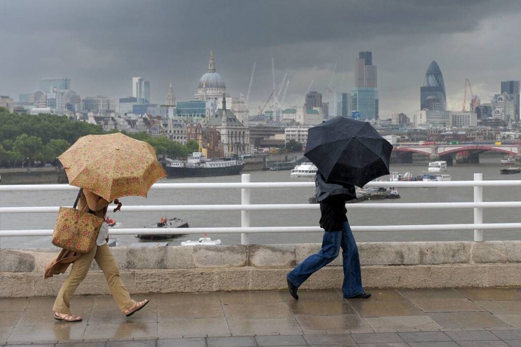 Pendler kämpfen mit Wind und Regen auf der London Bridge in einem der sonnenärmsten Länder der Welt