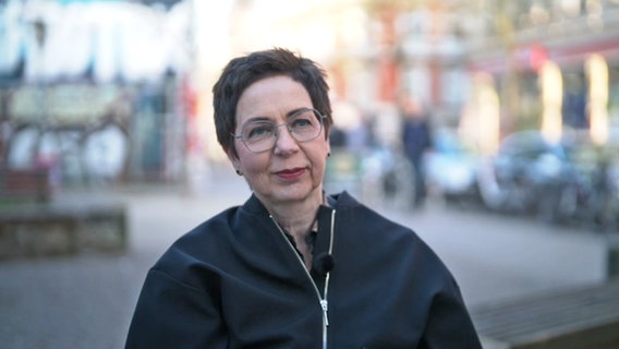 Eine Frau mit Brille, kurzen Haaren und dunkler Jacke schaut freundlich © NDR Screenshot 