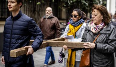 Menschen tragen großes Kreuz durch Altstadt