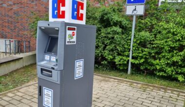 Hier steht ein einsamer Geldautomat auf dem Parkplatz