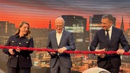 Mit einem symbolischen Schnitt durch ein rotes Seemannstau eröffnet Hamburgs Bürgermeister Peter Tschentscher (SPD) das Westfield Hamburg-Überseequartier in der Hafencity – gemeinsam mit Jean-Marie Tritant (r), CEO von Unibail-Rodamco-Westfield, und Theda J. Mustroph (l), die künftig das Quartiersmanagement übernimmt. © NDR Foto: Anna-Lena Ehle