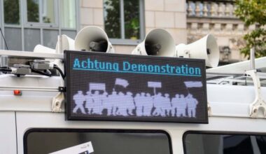 Polizeiwagen mit einer Warntafel, auf der steht Achtung Demonstration