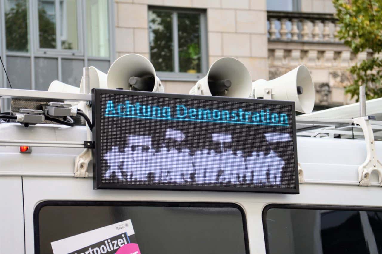 Polizeiwagen mit einer Warntafel, auf der steht Achtung Demonstration