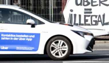 Archivbild: Ein Auto des Mietwagen-Anbieters Uber fährt in Berlin Mitte an einem Plakat mit der Aufschrift «Uber = Illegal» vorbei. (Quelle: dpa/Hofmann)