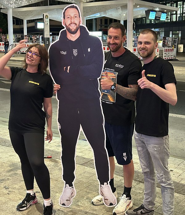 Trainer Mitch Kniat mit Nadine und Janik von Three Sixty und einer Pappfigur, die größer ist, als der Aufstiegscoach selbst. - © Julius Uekmann