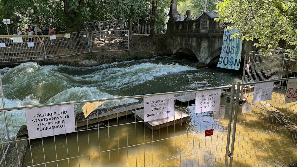 Die Verbotsschilder sind inzwischen deutlich in der Minderzahl: Am Einstieg zur Eisbachwelle wurden Plakate aufgehängt, auf denen die Sperrung kritisiert wird.