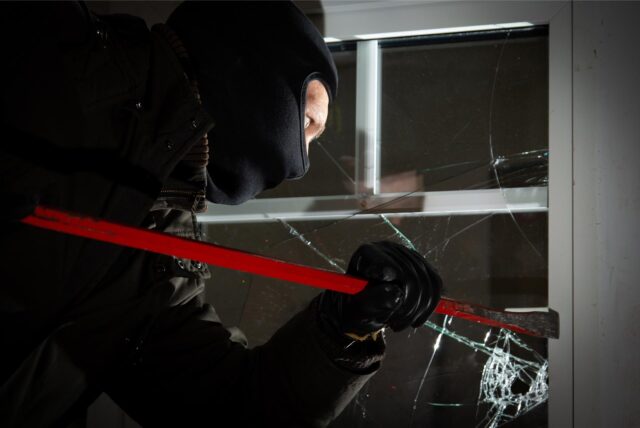 Ein vermummter Mann versucht, ein Fenster aufzuhebeln. (Symbolbild)