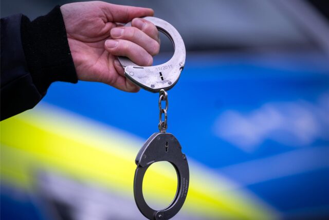 Ein Polizist hält ein Paar Handschellen